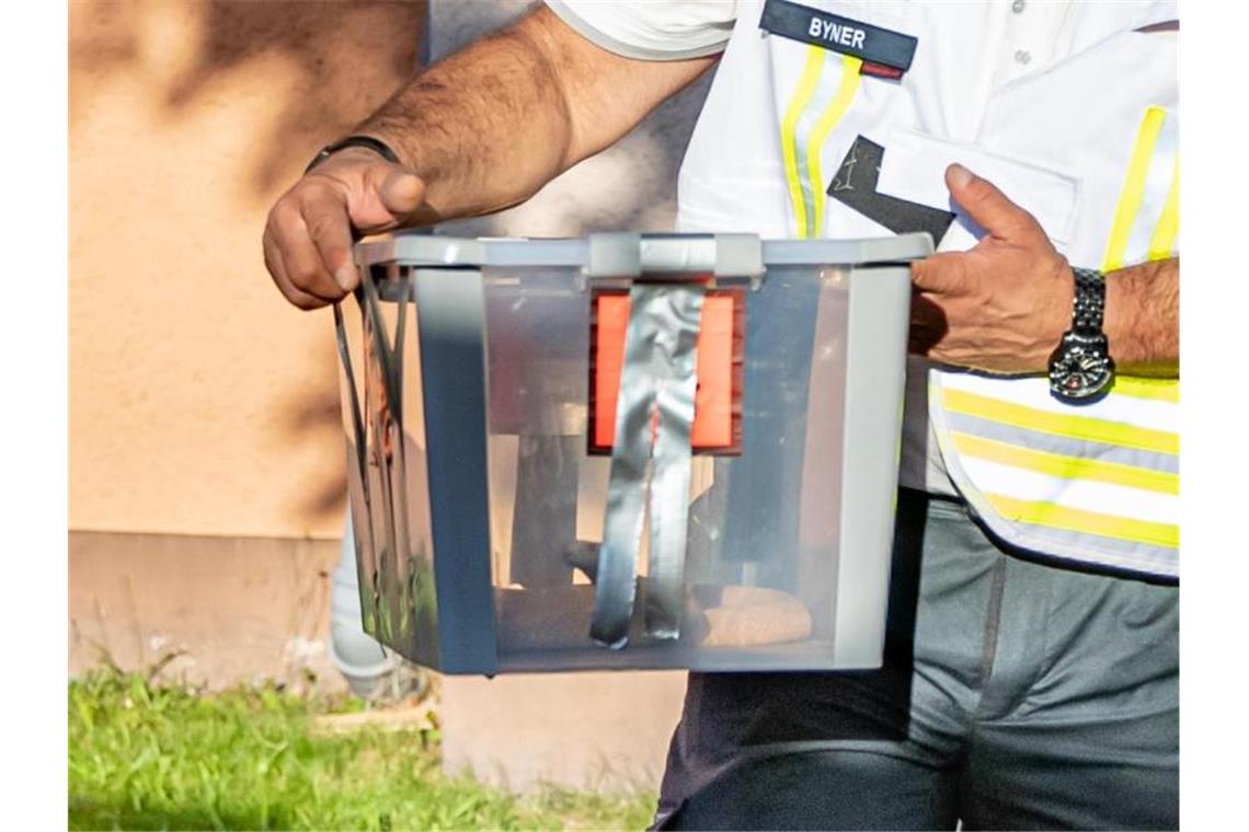 Giftschlange in Herne ist eingefangen Ein Reptilienexperte trägt die eingefangene Monokelkobra in einem Behälter aus einem Hauseingang. Foto: Marcel Kusch