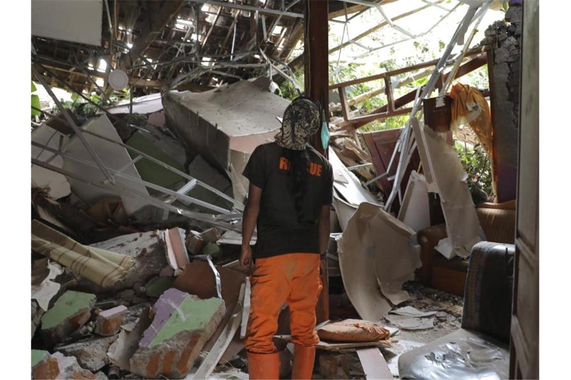 Mindestens zehn Tote nach Erdrutsch in Indonesien Ein Rettungshelfer inspiziert ein zerstörtes Haus im Dorf Nganjuk. Foto: Trisnadi/AP/dpa