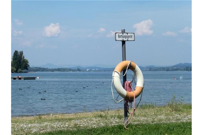 Ein Rettungsring hängt vor einem See. Foto: Tom Nebe/dpa-tmn/Archiv