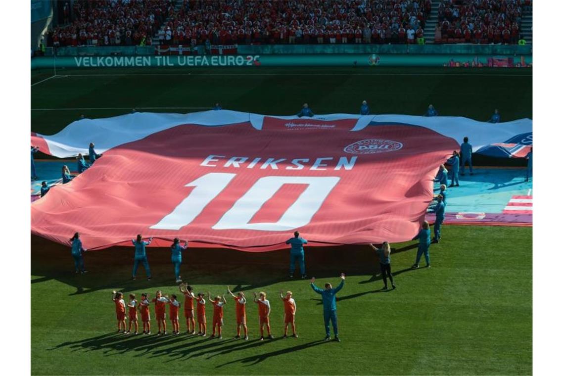 Ein riesiges Trikot zu Ehren des dänischen Spielers Eriksen wird vor dem Spiel auf das Spielfeld gebracht. Foto: Hannah Mckay/AP/dpa