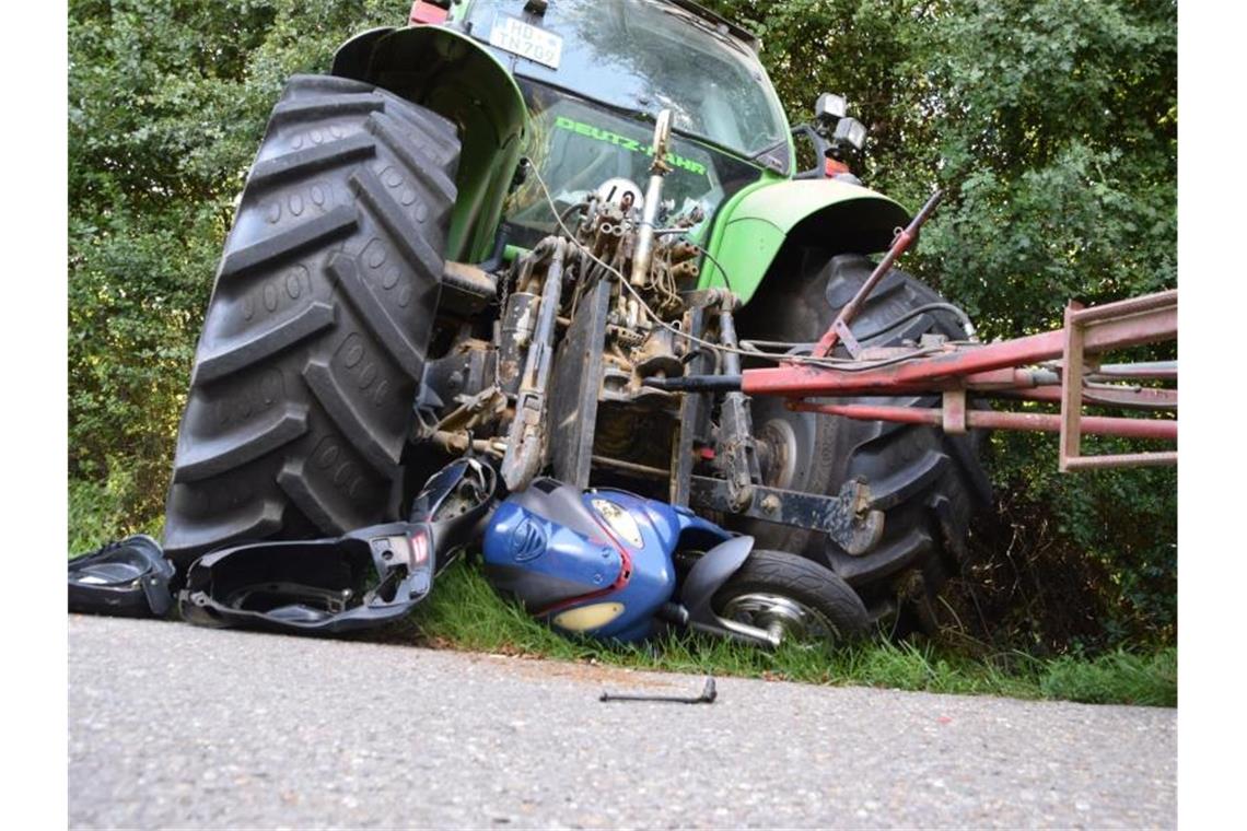 Ein Roller liegt eingequetscht unter einem Traktor am Wegesrand. Foto: Julian Buchner