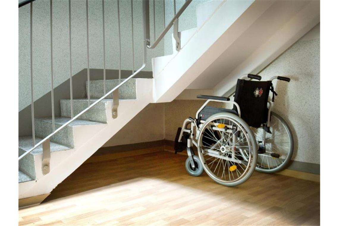 Ein Rollstuhl steht unter einer Treppe in einem Wohnhaus. Foto: Arno Burgi/zb/dpa/Symbolbild