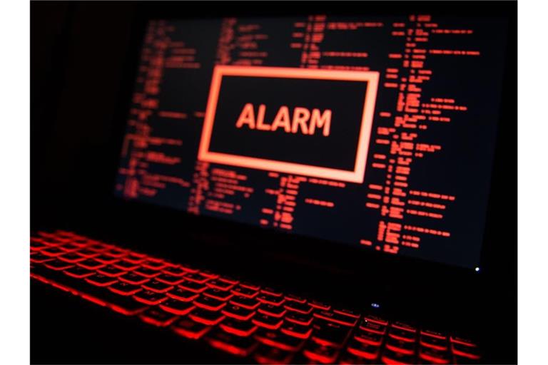 Ein rot beleuchteter Computer zeigt eine fiktive Fehlermeldung an (gestellte Szene). Foto: Lino Mirgeler/dpa/Illustration