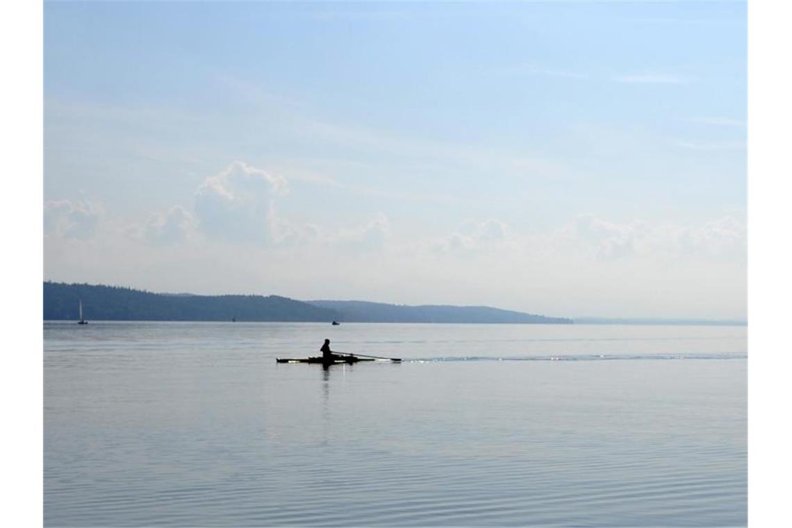 Ein Ruderer fährt bei Sonnenschein über den Starnberger See (Oberbayern). Foto: Andreas Gebert/dpa