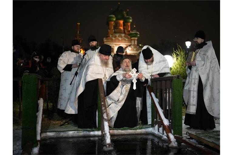 Ein russisch-orthodoxer Priester segnet am Dreikönigstag das eiskalte Wasser in der Kirche der Heiligen Dreifaltigkeit in Moskau. Foto: Alexander Zemlianichenko/AP/dpa