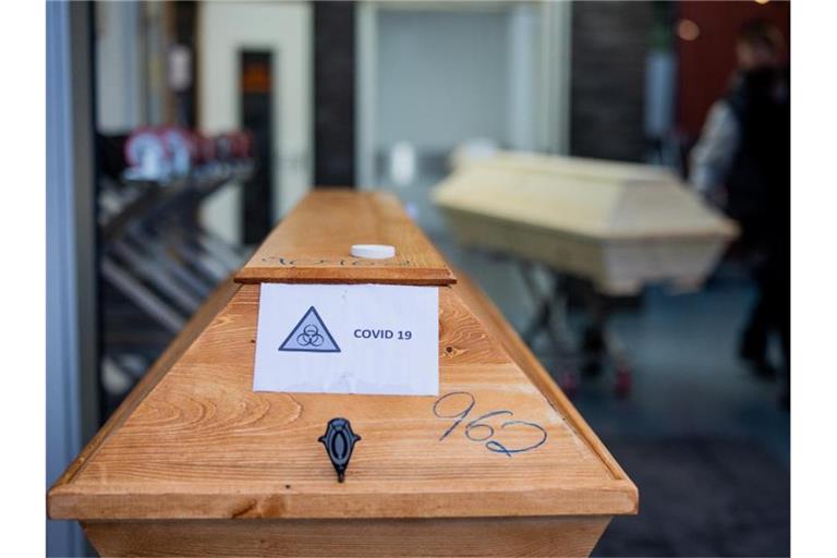 Ein Sarg mit der Aufschrift „Covid 19“ und dem Zeichen „Biohazard“ steht in einem Krematorium. Foto: Rolf Vennenbernd/dpa