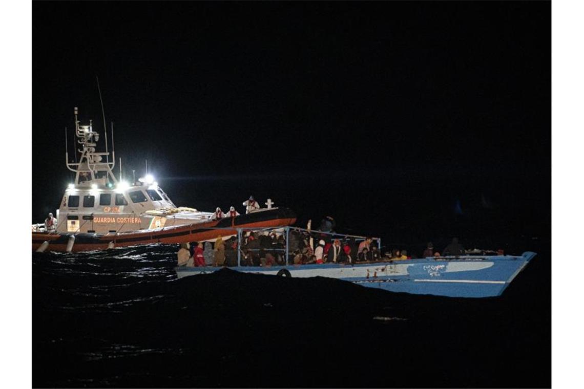 Ein Schiff der Küstenwache fährt zu dem völlig überfüllten Holzboot vor Lampedusa. Foto: Pau De La Calle/AP/dpa