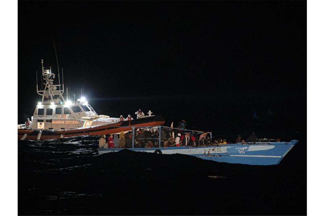 Erfroren: Sieben Tote auf Migrantenboot vor Lampedusa Ein Schiff der Küstenwache fährt zu dem völlig überfüllten Holzboot vor Lampedusa. Foto: Pau De La Calle/AP/dpa