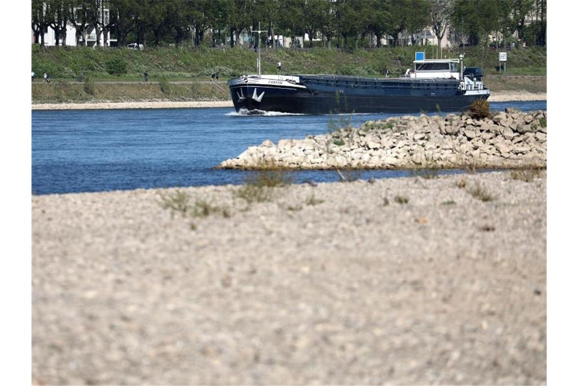 Ein Schiff fährt hinter einer freiliegenden Sandbank über den Rhein. Foto: Oliver Berg/dpa/Archivbild