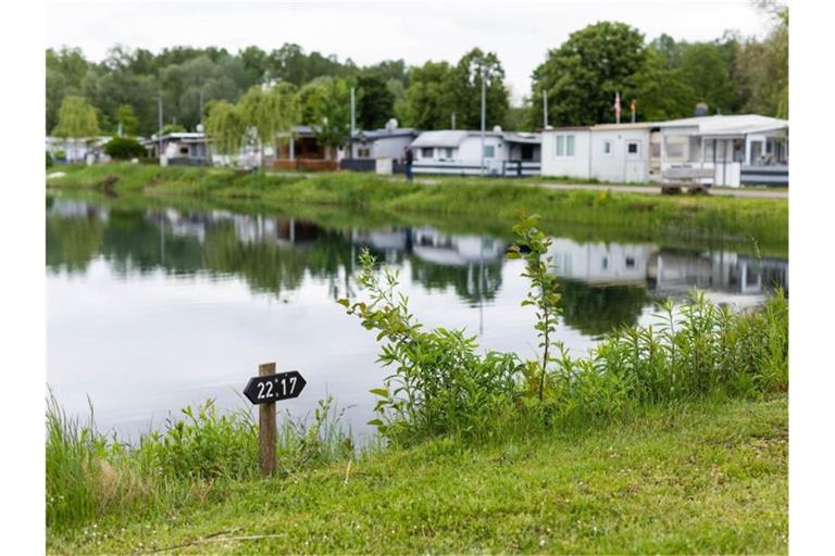 Ein Schild auf einem Campingplatz weist Stellplätze aus, im Hintergrund stehen Wohnwägen von Dauercampern. Foto: Philipp von Ditfurth/dpa/Archivbild