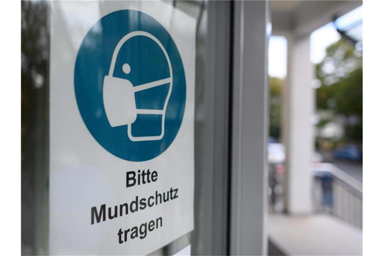 Ein Schild "Bitte Mundschutz tragen" ist an einer Tür angebracht. Foto: Robert Michael/dpa-Zentralbild/ZB/Symbolbild