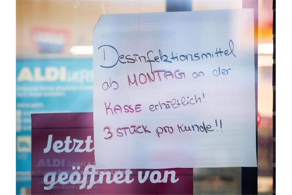 Ein Schild „Desinfektionsmittel ab Montag an der Kasse erhältlich! 3 Stück pro Kunde!!“ hängt an der Eingangstür eines Aldi-Marktes. Foto: Julian Stratenschulte/dpa