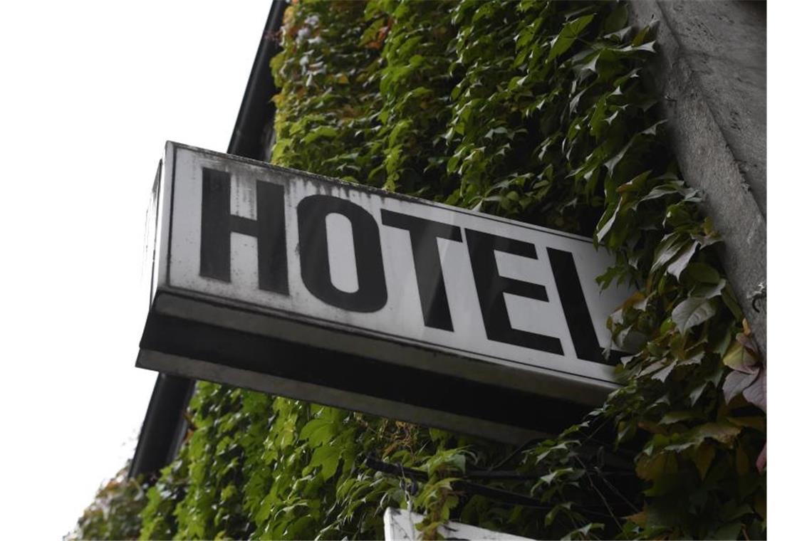Ein Schild "Hotel" ist an der mit Efeu bewachsenden Wand eines Gebäudes angebracht. Foto: Roberto Pfeil/dpa/Illustration