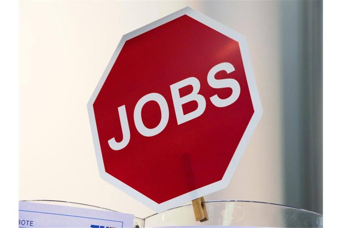 Ein Schild in der Form eines Stoppschildes mit der Aufschrift „Jobs“ hängt an einem Messestand. Foto: Martin Schutt/Archivbild