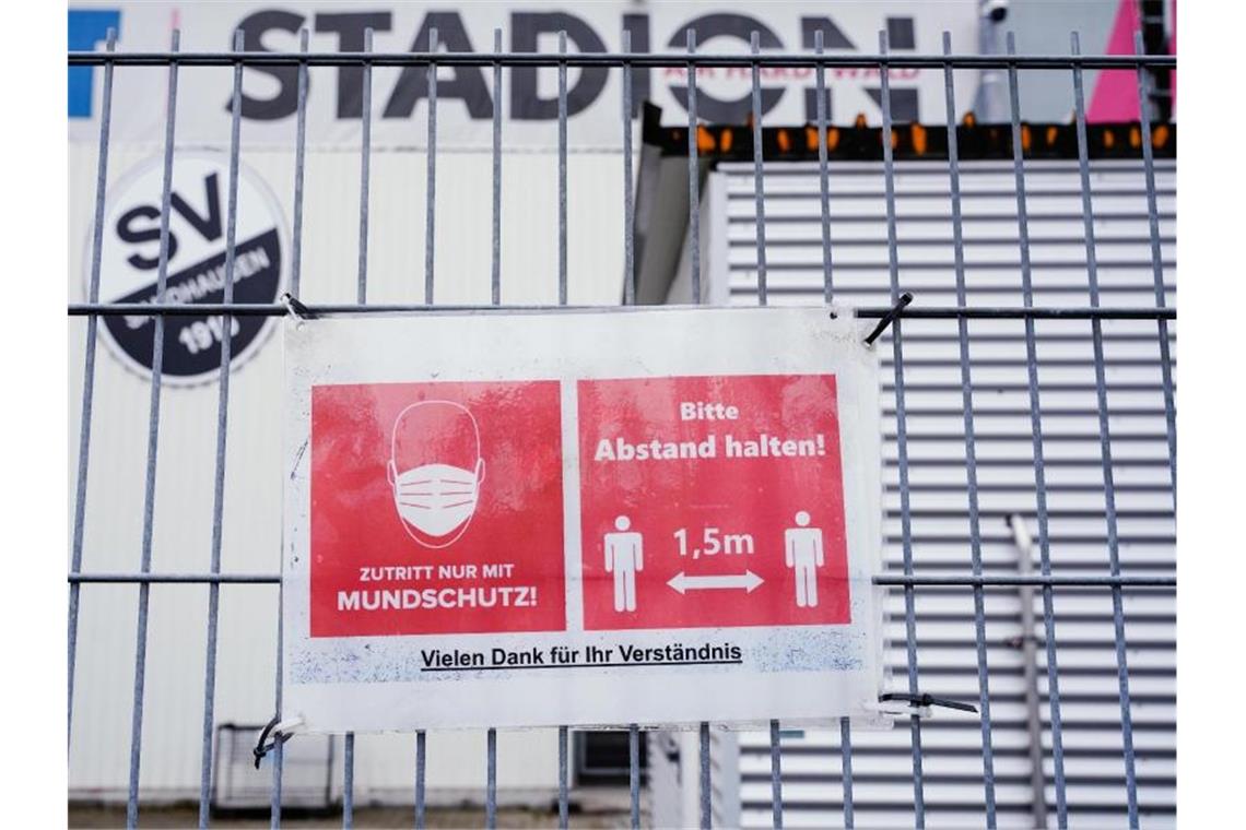 Ein Schild mit Corona-Informationen hängt an einem Zaun vor dem BWT-Stadion am Hardtwald. Foto: Uwe Anspach/dpa/Bildarchiv