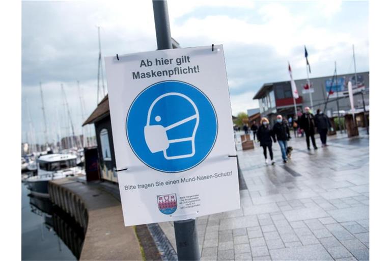 Ein Schild mit der Aufschrift „Ab hier gilt Maskenpflicht“ hängt an der Promenade. Foto: Daniel Bockwoldt/dpa