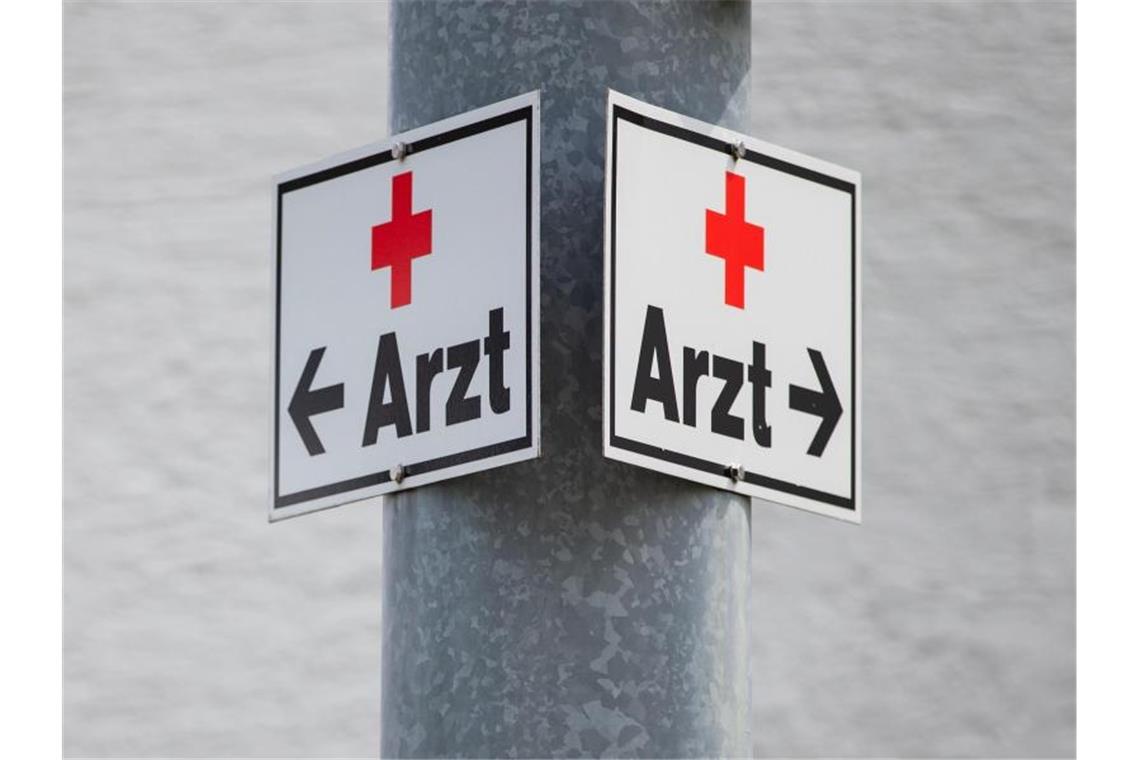 Ein Schild mit der Aufschrift „Arzt“ hängt an einer Straßenlaterne. Foto: Tom Weller/dpa/Symbolbild