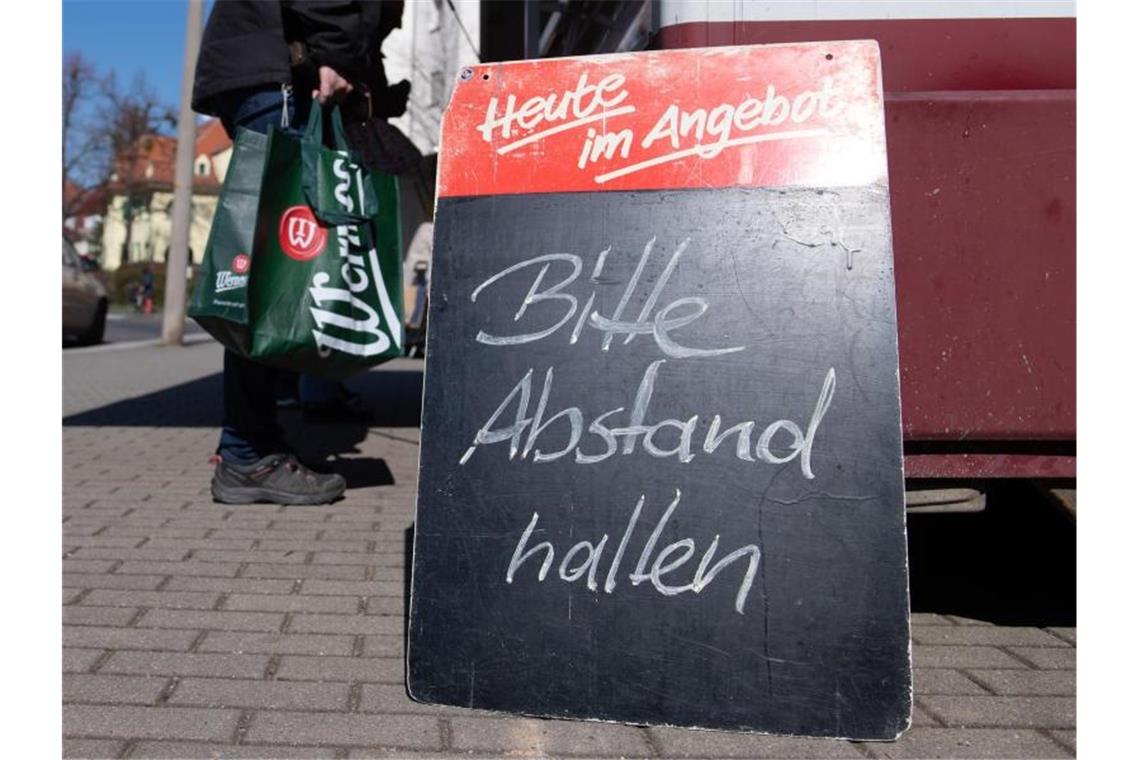 Wissenschaftler: Lockerung nach Osterferien denkbar Ein Schild mit der Aufschrift „Bitte Abstand halten“ auf einem Wochenmarkt. Foto: Sebastian Kahnert/dpa-Zentralbild/dpa