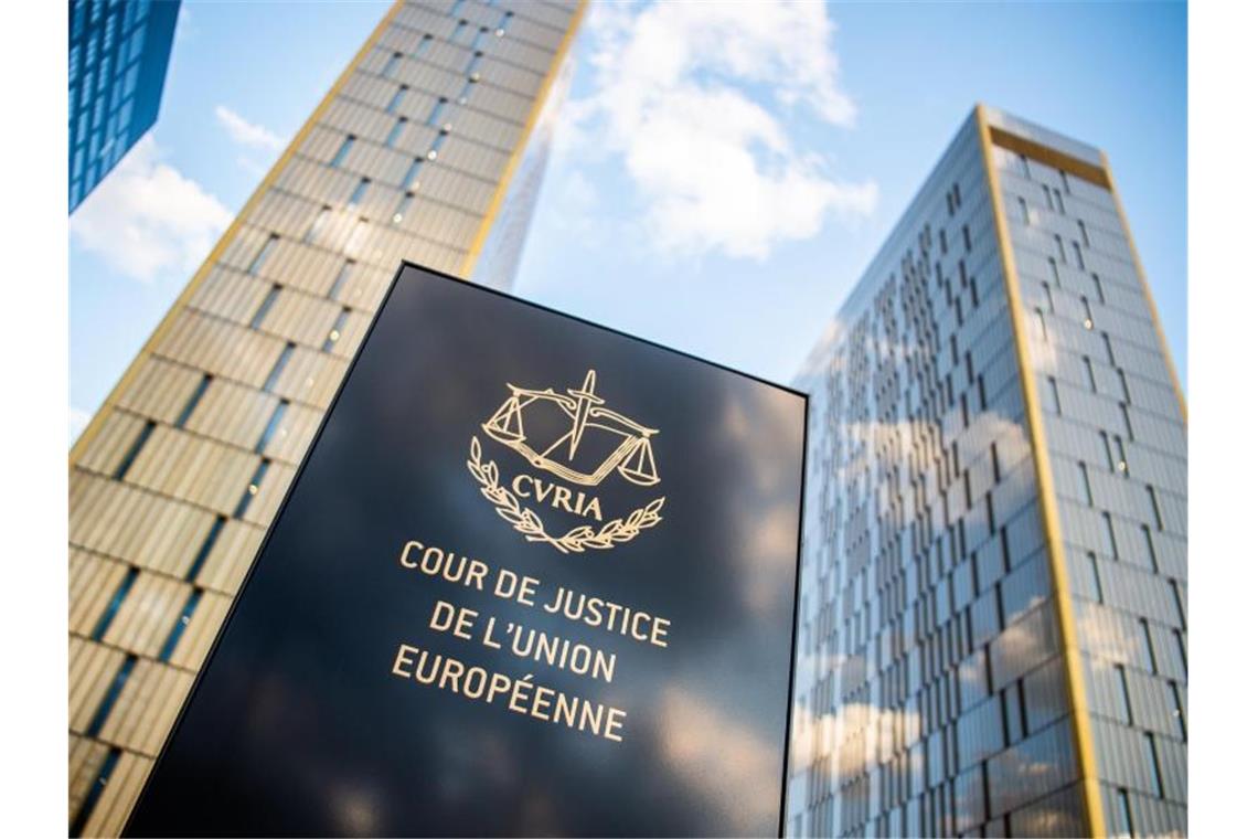 Ein Schild mit der Aufschrift „Cour de Justice de l'union Européene“ steht vor den Türmen des EuGH. Foto: Arne Immanuel Bänsch/dpa/archivbild