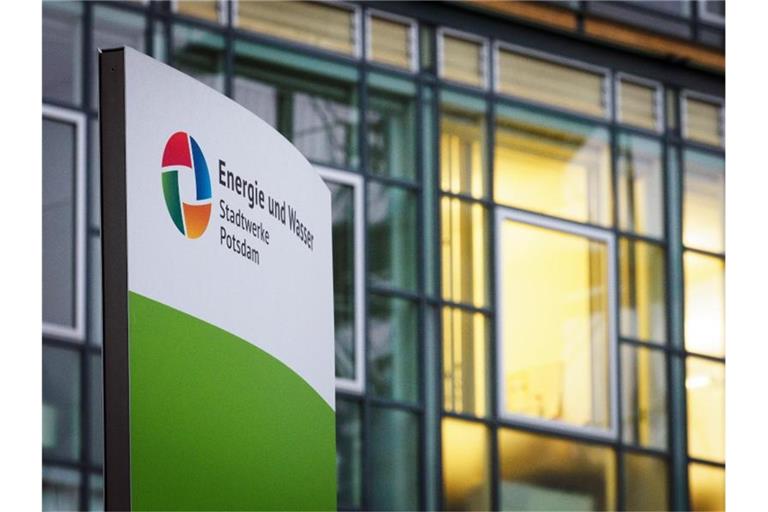 Ein Schild mit der Aufschrift „Energie und Wasser“ steht vor beleuchteten Büros am Eingang zu den Potsdamer Stadtwerken. Foto: Soeren Stache/dpa-Zentralbild/dpa