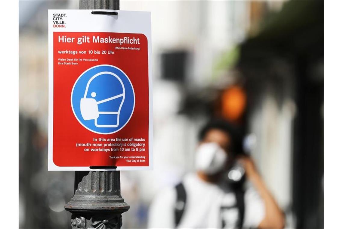Ein Schild mit der Aufschrift „Hier gilt Maskenpflicht“ hängt in der Fußgängerzone in Bonn. Erstmals seit drei Wochen liegt die 7-Tage-Inzidenz in Deutschland wieder höher als am Vortag. Foto: Oliver Berg/dpa