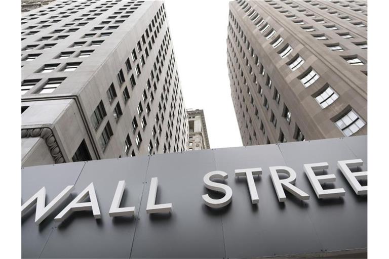 Ein Schild mit der Aufschrift „Wall Street“ hängt an der Fassade der New Yorker Börse. Foto: Mark Lennihan/AP/dpa