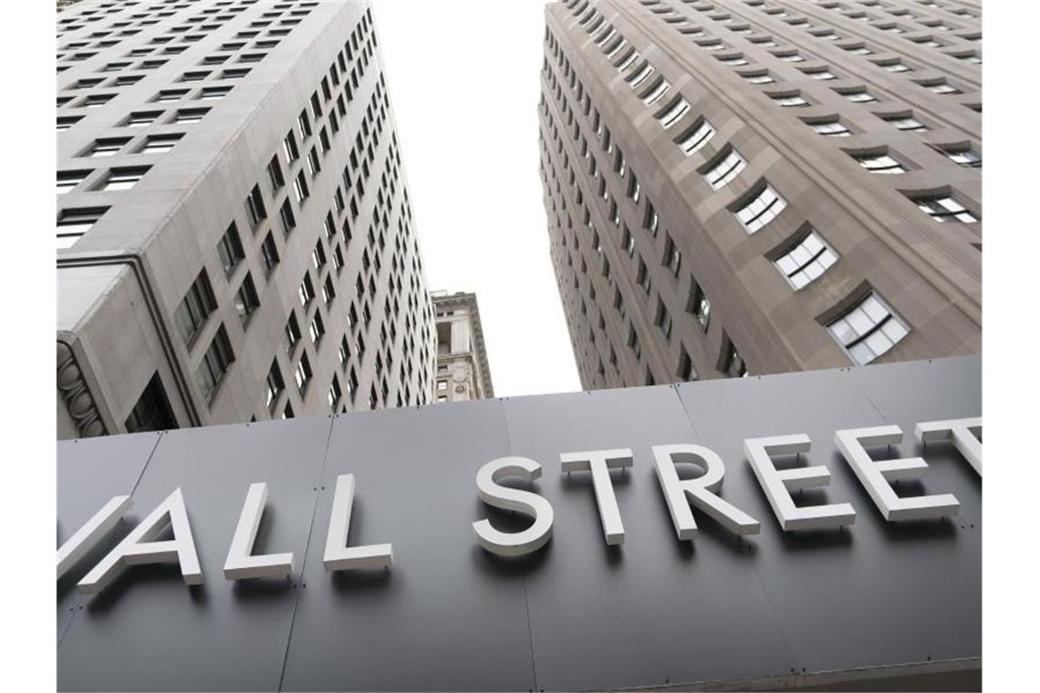 Ein Schild mit der Aufschrift „Wall Street“ hängt an der Fassade der New Yorker Börse. In den USA haben die Standardwerte-Börsen am Montag geschwächelt. Foto: Mark Lennihan/AP/dpa