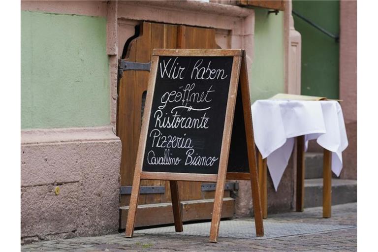Ein Schild mit der Aufschrift „Wir haben geöffnet“ steht vor einem Restaurant in der Innenstadt. Foto: Uwe Anspach/dpa/aktuell