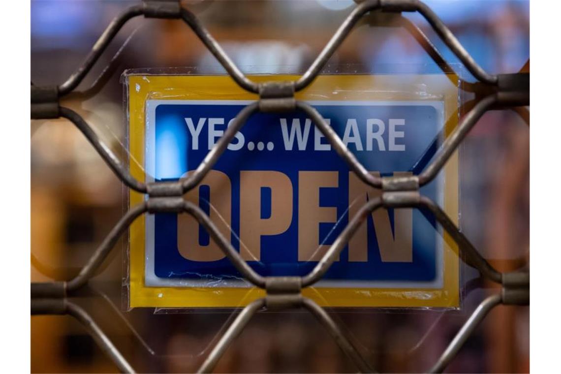 Ein Schild mit der Aufschrift „Yes... we are Open“ ist an einem geschlossenen Geschäft in München zu sehen. Foto: Sven Hoppe/dpa