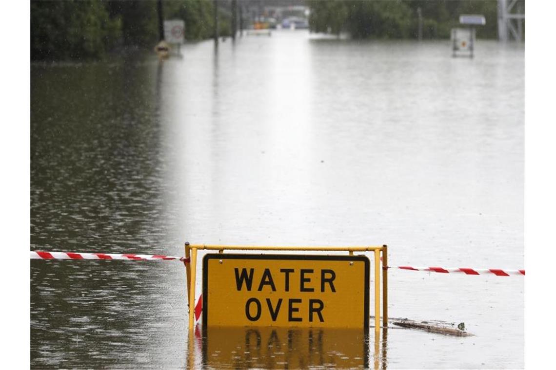 Ein Schild mit Warnhinweis auf einer überfluteten Straße bei Windsor. Tagelanger Starkregen hat im Osten Australiens die schlimmsten Überschwemmungen seit Jahrzehnten ausgelöst. Foto: Rick Rycroft/AP/dpa
