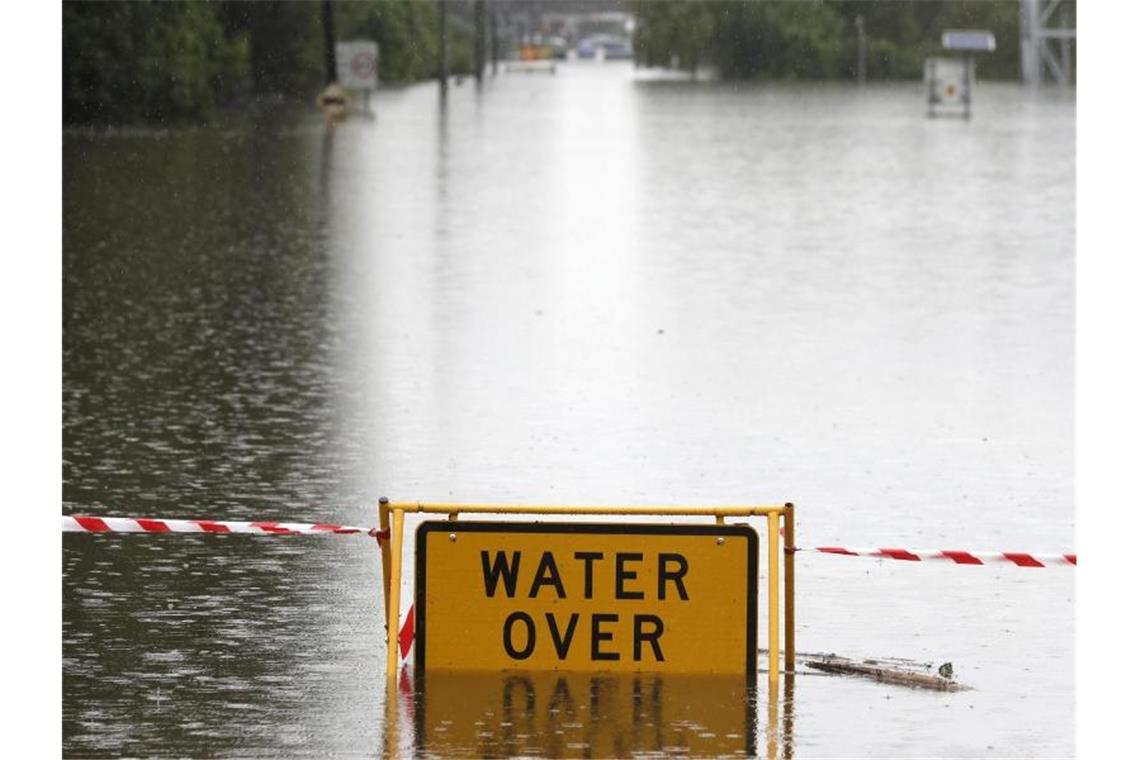 Keine Entwarnung bei Überschwemmungen in Australien Ein Schild mit Warnhinweis auf einer überfluteten Straße bei Windsor. Tagelanger Starkregen hat im Osten Australiens die schlimmsten Überschwemmungen seit Jahrzehnten ausgelöst. Foto: Rick Rycroft/AP/dpa