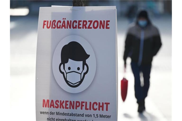 Ein Schild weist auf die Maskenpflicht in der Fußgängerzone hin. Foto: Marijan Murat/dpa