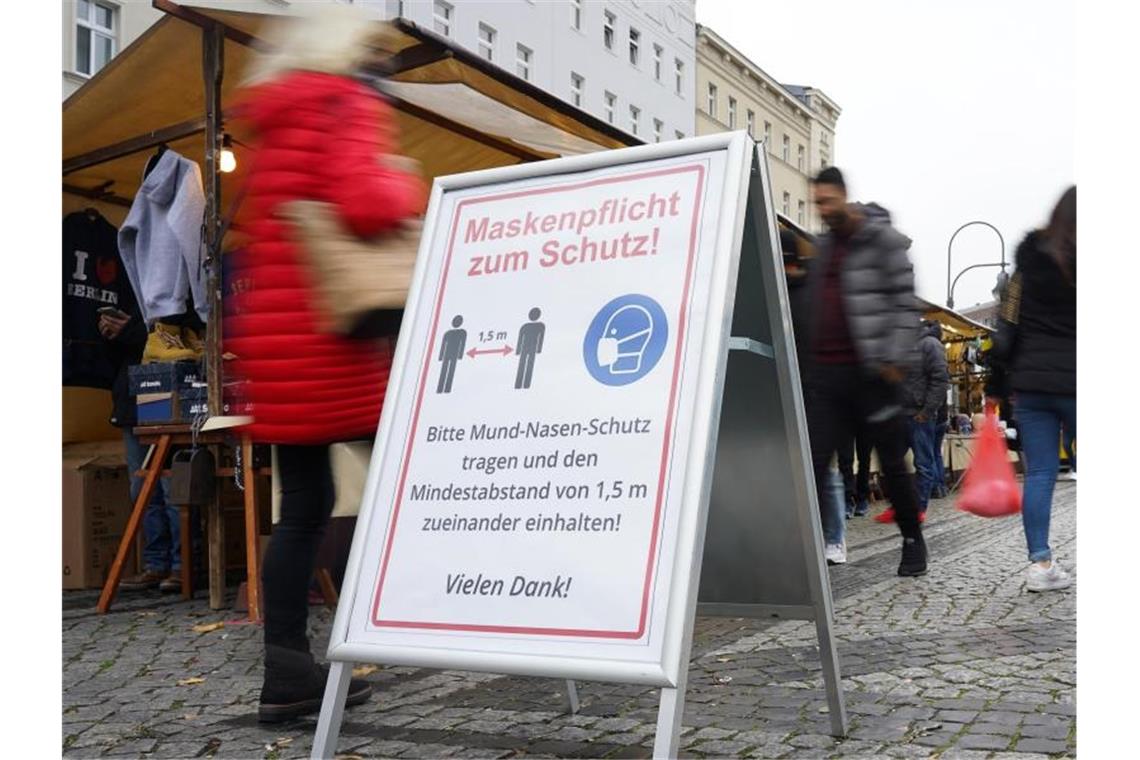 Ein Schild weist auf einem Wochenmarkt in Berlin auf Maskenpflicht und Abstandsgebot hin. Foto: Jörg Carstensen/dpa
