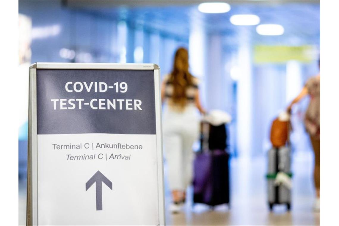 Ein Schild weist Reisende in einem Flughafen auf das Corona-Testzentrum hin. Foto: Moritz Frankenberg/dpa
