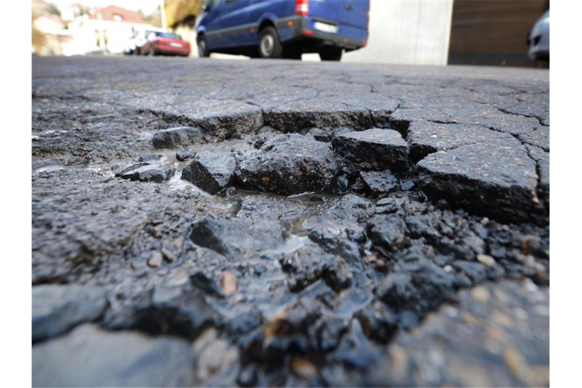 Ein Schlagloch ist auf einer Straße zu sehen. Foto: picture alliance / dpa/Archivbild