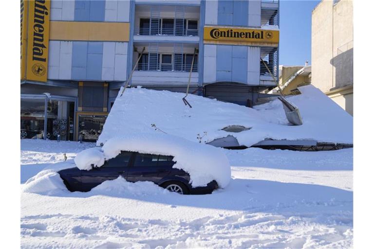 Ein schneebedecktes Auto steht vor einem beschädigten Gebäude. Über dem Großraum Athen waren ungewöhnlich starke Schneefälle niedergegangen. Foto: Thanassis Stavrakis/AP/dpa