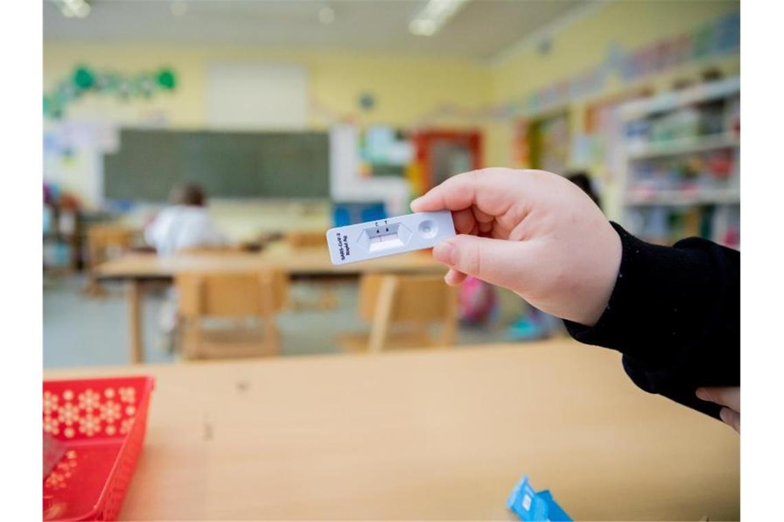 Kultusminister planen Corona-Schalte - Debatte über Schulen Ein Schüler hält bei einem Probelauf mit Corona-Schnelltests an einer Berliner Grundschule seinen negativen Test in die Kamera. Foto: Christoph Soeder/dpa