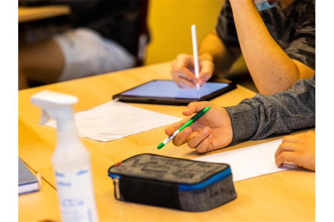 Ein Schüler hält beim Unterricht in seiner Klasse einen Stift, während ein anderer mit einem Tablet arbeitet. Foto: Philipp von Ditfurth/dpa