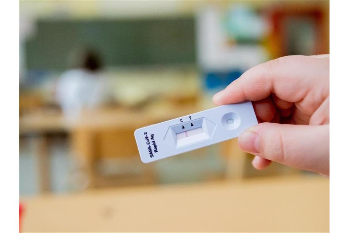 Ein Schüler hält einen negativen Test in die Kamera. Foto: Christoph Soeder/dpa/Aktuell