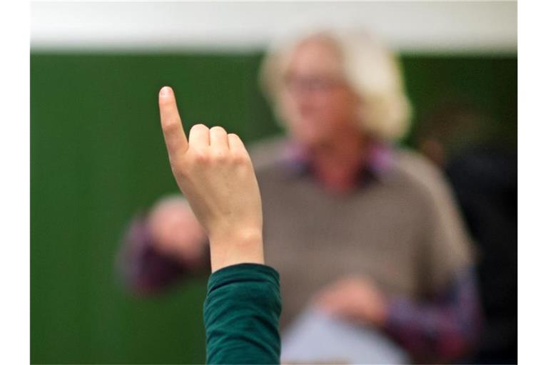 Ein Schüler meldet sich um eine Frage zu beantworten. Foto: Julian Stratenschulte/dpa/Symbolbild