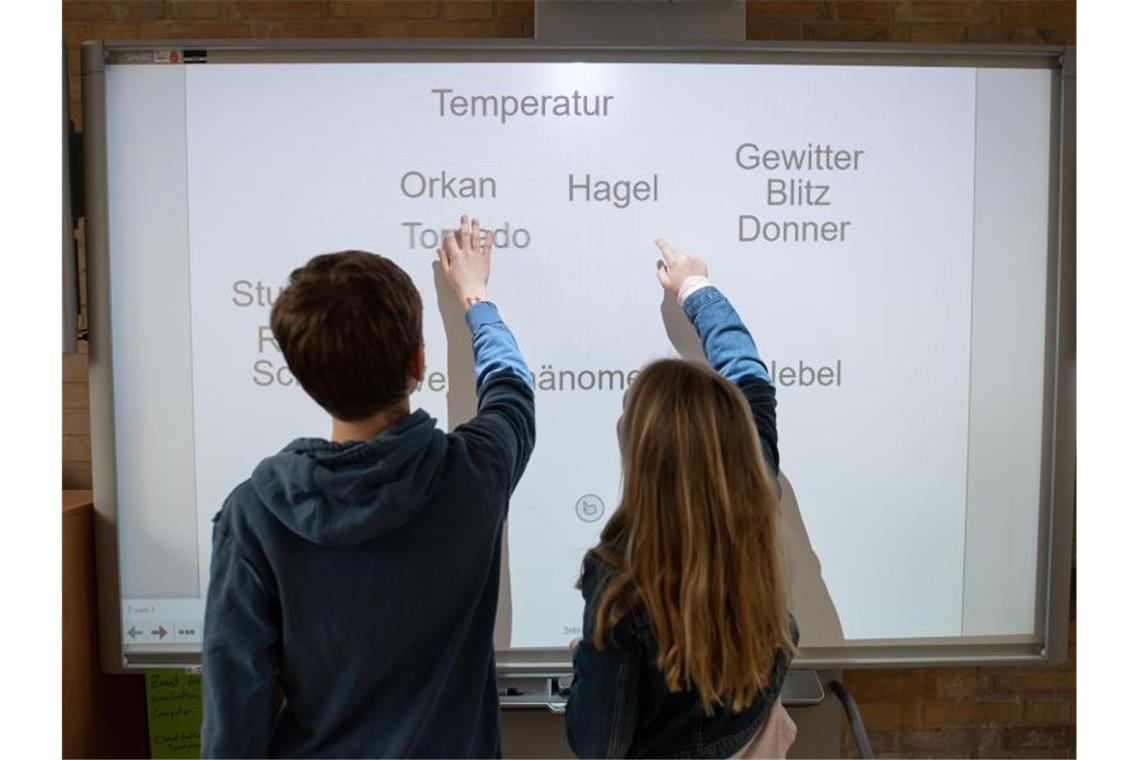 Ein Schüler und eine Schülerin arbeiten an einem Smartboard. Foto: Daniel Reinhardt/dpa