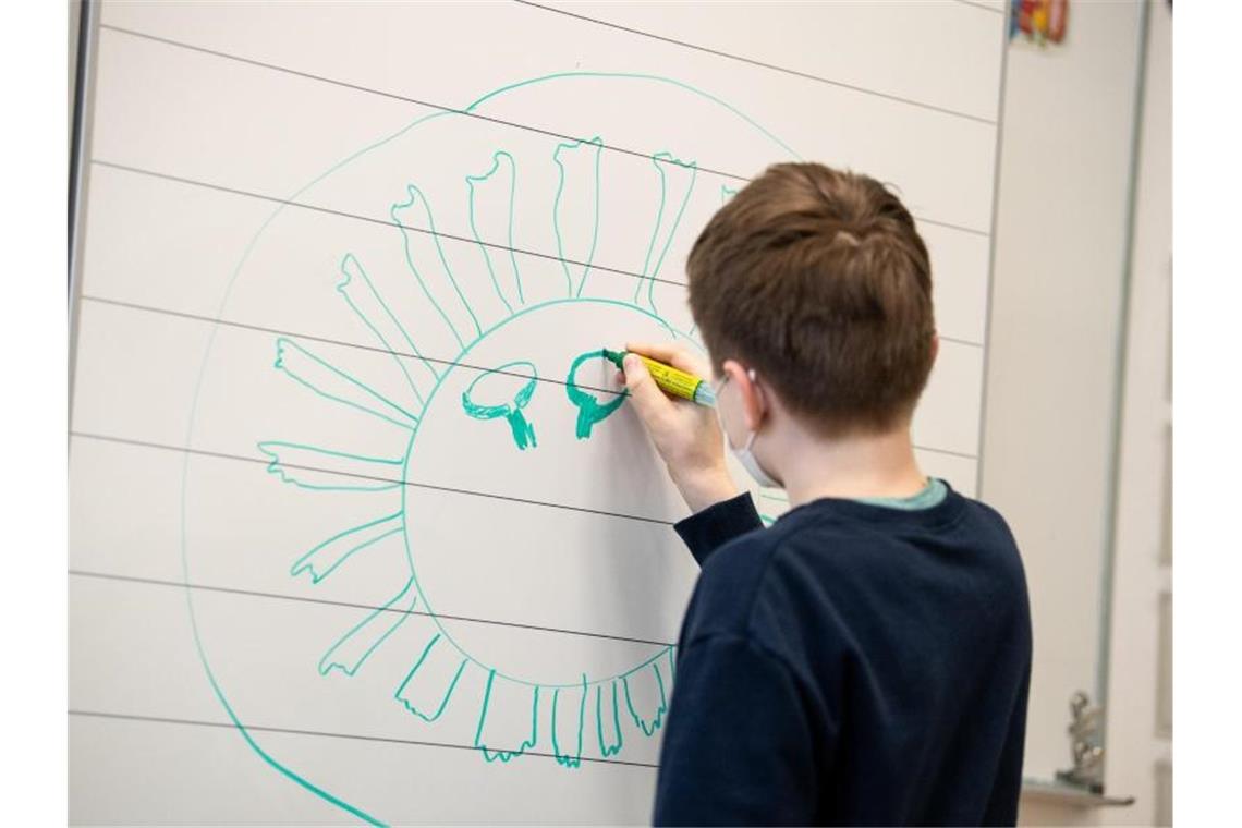 Ein Schüler zeichnet ein Corona-Virus an die Tafel. Foto: Matthias Balk/dpa