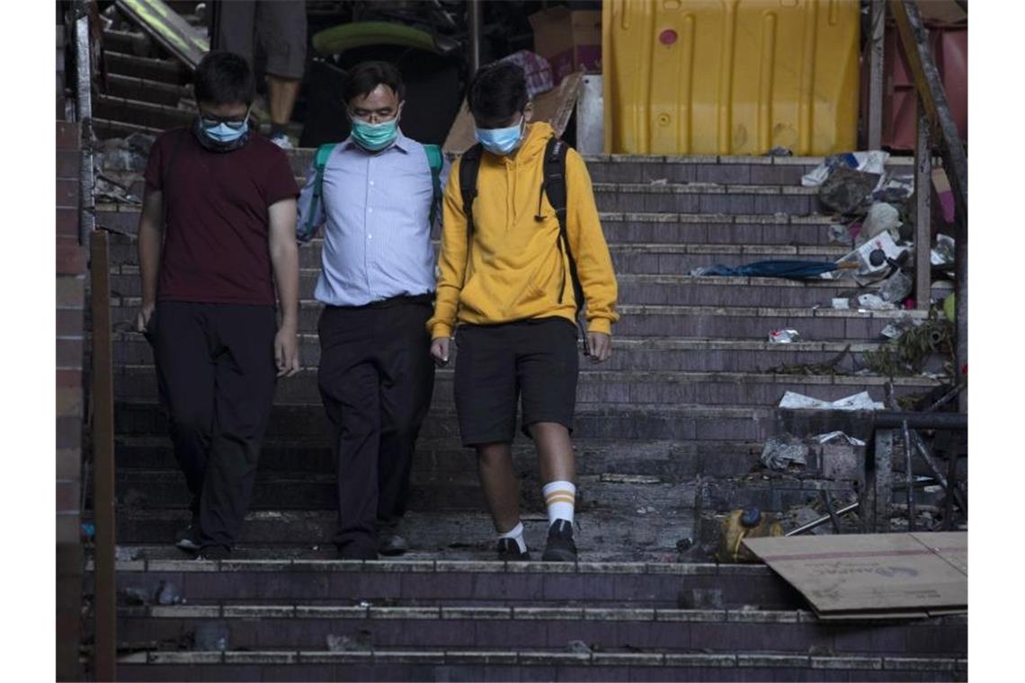 Hongkong: US-Kongress stellt sich hinter Demokratiebewegung Ein Schulleiter begleitet zwei Jugendliche, die sich der Polizei stellen. Foto: Ng Han Guan/AP/dpa