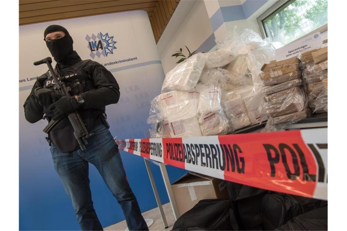 Ein schwer bewaffneter und vermummter Polizist bewacht während einer Pressekonferenz im bayerischen Landeskriminalamt etwa 640 Kilo Kokain, Waffen und Bargeld. Foto: Peter Kneffel/dpa