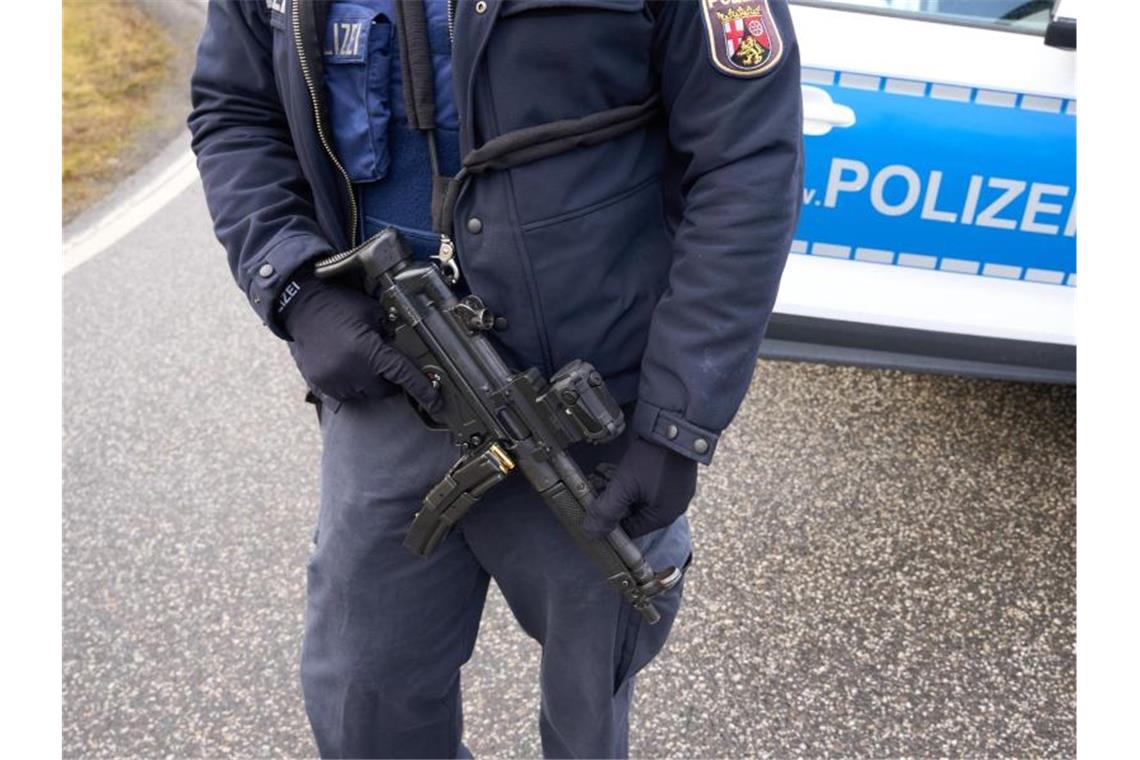 Polizisten erschossen - Zwei Verdächtige festgenommen Ein schwerbewaffneter Polizist steht an der Straßensperre. Foto: Thomas Frey/dpa
