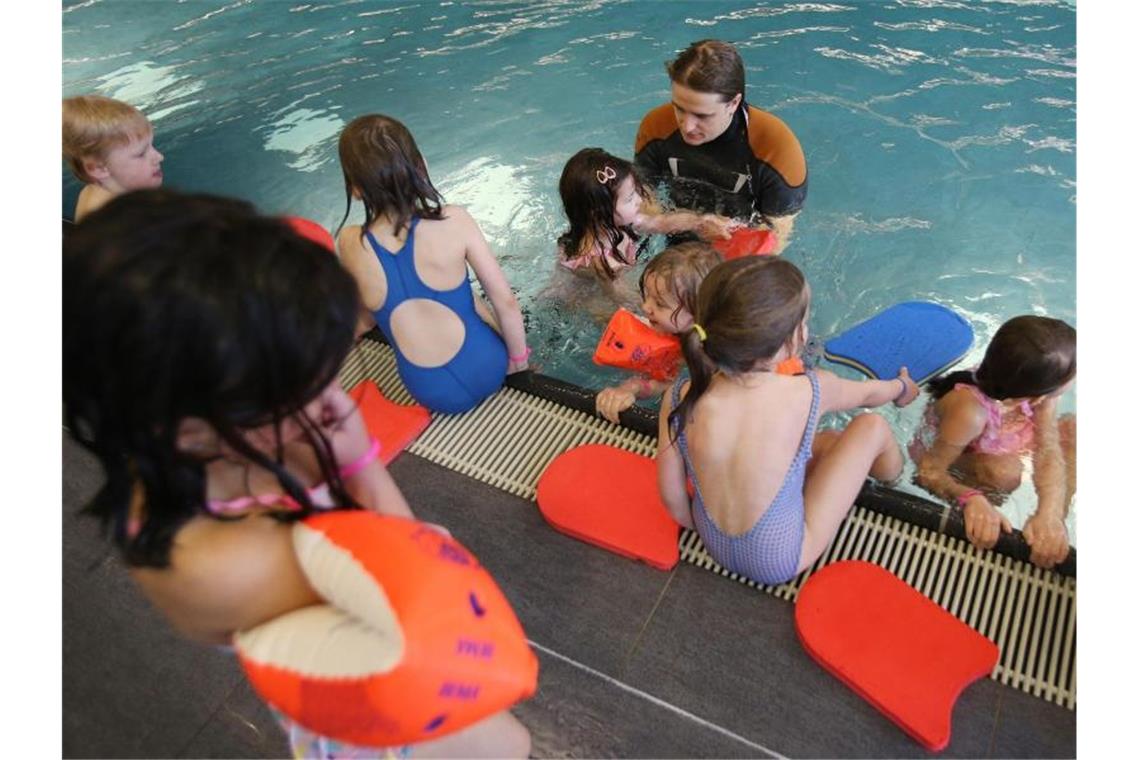 Ein Schwimmlehrer gibt Kindern Schwimmuntericht. Foto: Christian Charisius/Archivbild