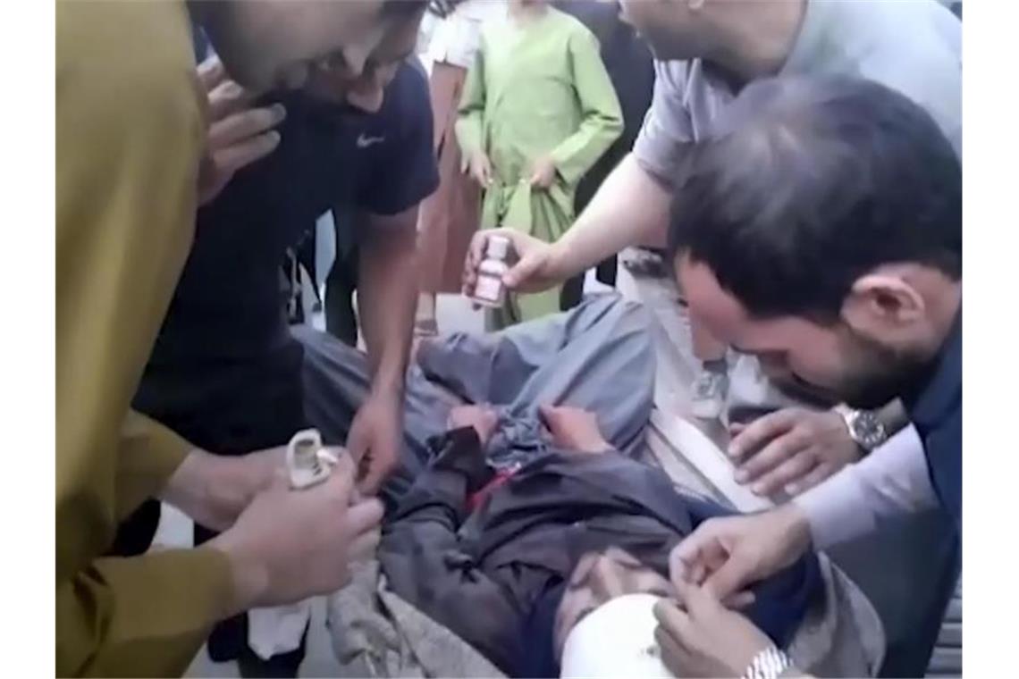 Nach Blutbad von Kabul: Biden kündigt Vergeltung an Ein Screenshot aus einem Video zeigt Menschen, die sich um einen Verwundeten in der Nähe des Explosionsortes kümmern. Foto: Uncredited/AP/dpa