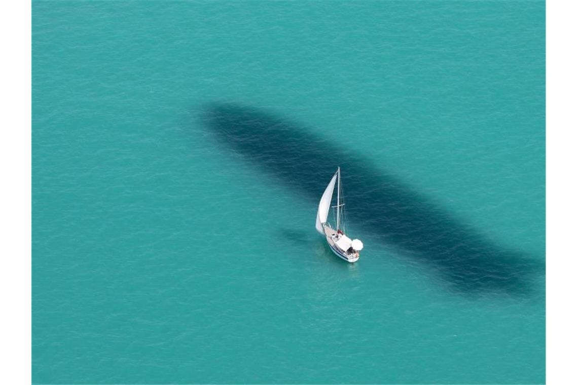 Höchste Temperatur des Jahres geknackt Ein Segelboot ist auf dem Bodensee unterwegs, während neben dem Boot der Schatten eines Zeppelin NT im Wasser zu sehen ist. Foto: Thomas Warnack/dpa