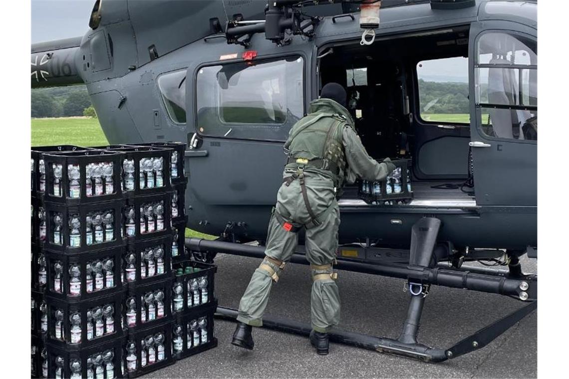 Ein Soldat entlädt am Nürburgring Kisten mit Trinkwasser aus einem Hubschrauber. Foto: Luftwaffe/dpa