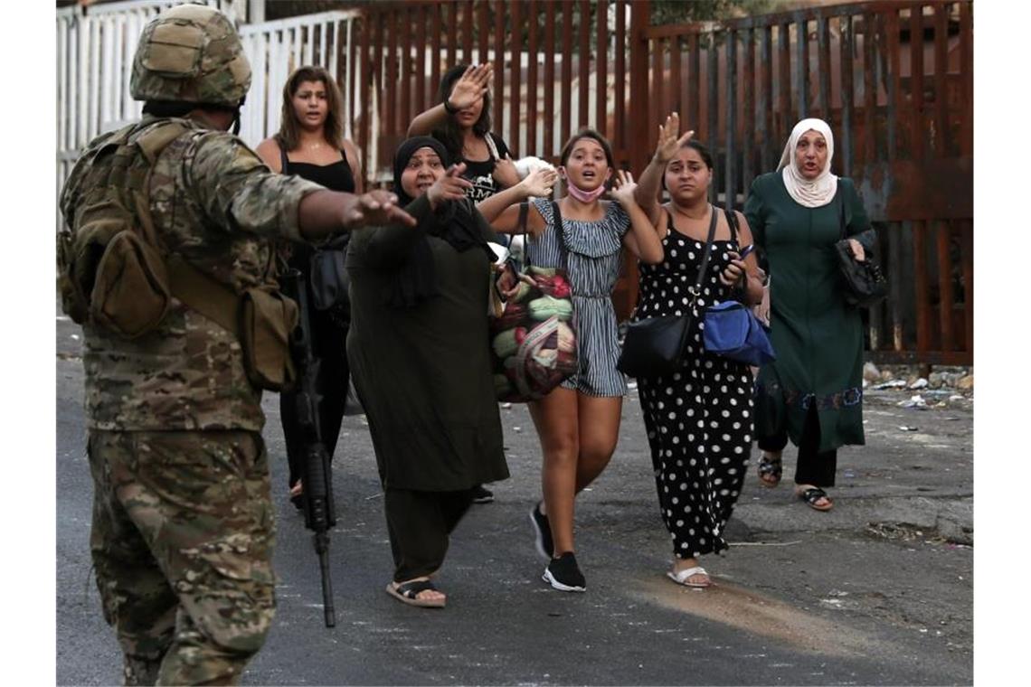 Fünf Tote bei bewaffneten Zusammenstößen im Libanon Ein Soldat evakuiert eine Gruppe Frauen nach Schüssen in der libanesischen Küstenstadt Khaldeh. Foto: Bilal Hussein/AP/dpa